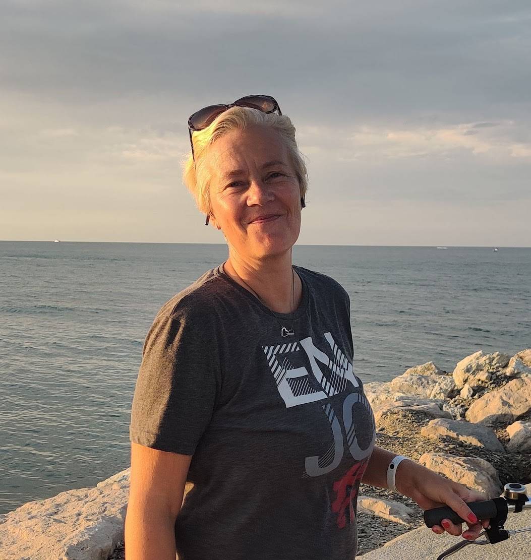 Ritratto attuale di Satu Bianchi sorridente sulla spiaggia di Rimini, pronta a mettere la sua esperienza al servizio delle aziende locali.