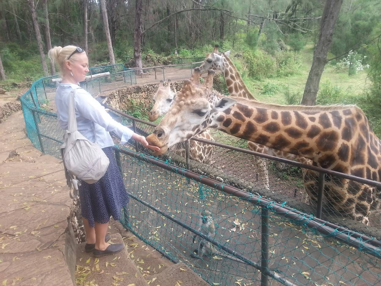 Satu Bianchi nutre con calma una giraffa, a simboleggiare la sua pazienza e la sua abilità nel creare un rapporto di fiducia.